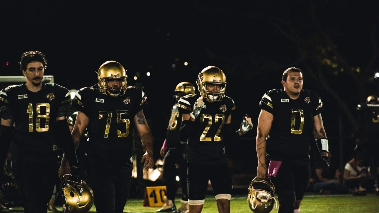 Alajuela Pumas players walking onto the field at night
