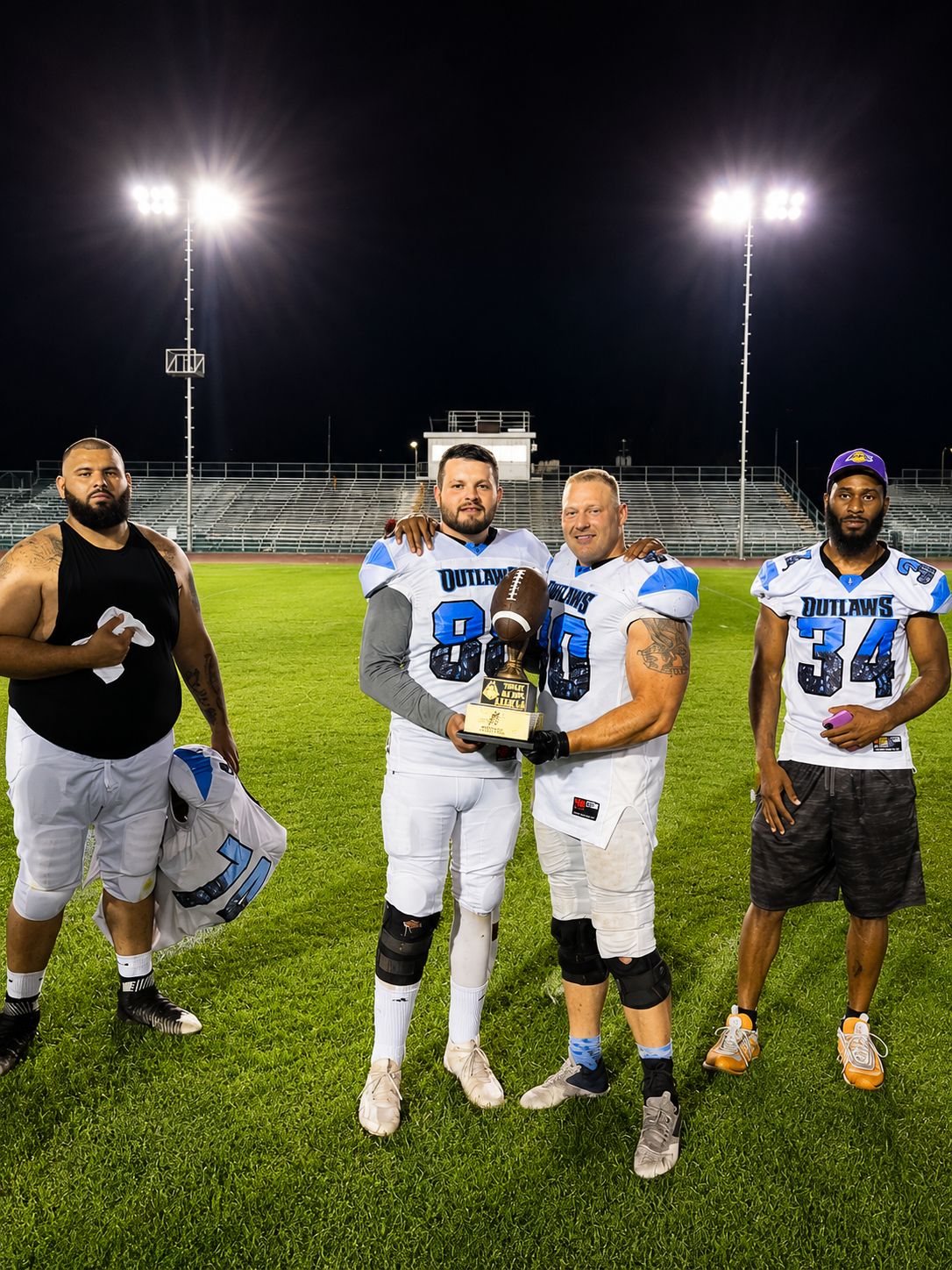 Phoenix Outlaws players holding their championship trophy beneath the stadium lights