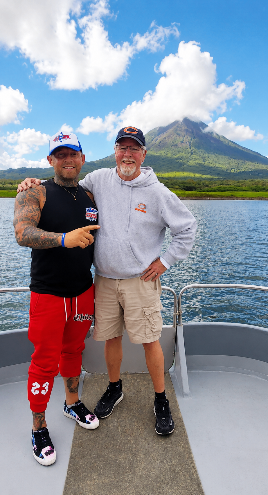 Ian and a supporter together on a boat with a volcano behind them